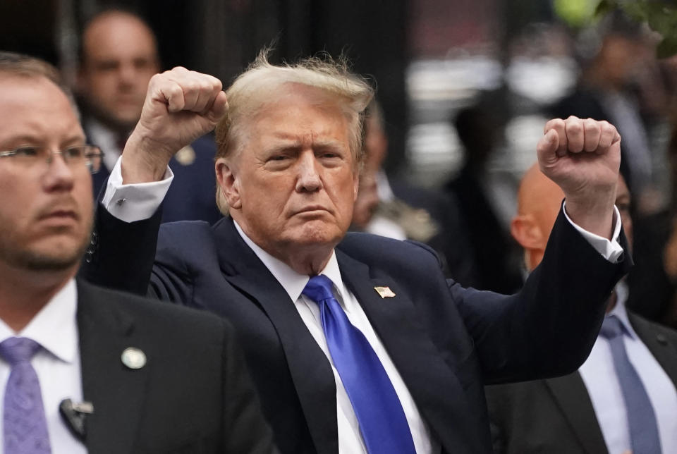 Donald Trump raises his fists while walking with security personnel in an outdoor setting