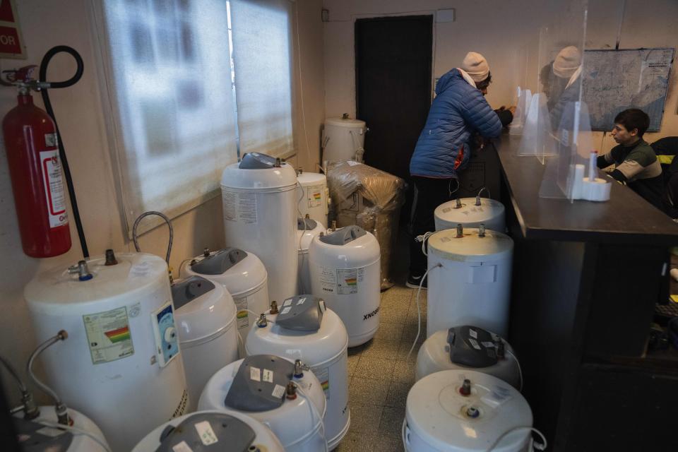 Customers fill out a form after leaving their water heaters for repair, in Montevideo, Uruguay, Thursday, June 22, 2023. According to a worker, most of them are broken due to the amount of mud and chlorine present in the water. (AP Photo/Matilde Campodonico)