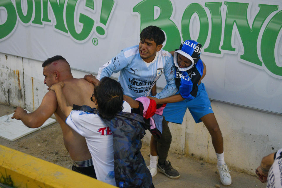 Fans clash during a Mexican soccer league match between the host Queretaro and Atlas from Guadalajara, at the Corregidora stadium, in Queretaro, Mexico, Saturday, March 5, 2022. Multiple people were injured during the brawl, including two critically. (AP Photo/Sergio Gonzalez)