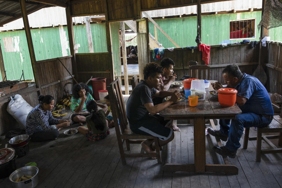 Barbaran family members eat lunch prior to the burial ceremony of their relative Jose Barbaran who is believed to have died from complications related to the new coronavirus, in Palestina, in Peru's Ucayali region, Wednesday, Sept. 30, 2020. As Peru grapples with one of the world's worst virus outbreaks, another epidemic is starting to raise alarm: Dengue. (AP Photo/Rodrigo Abd)