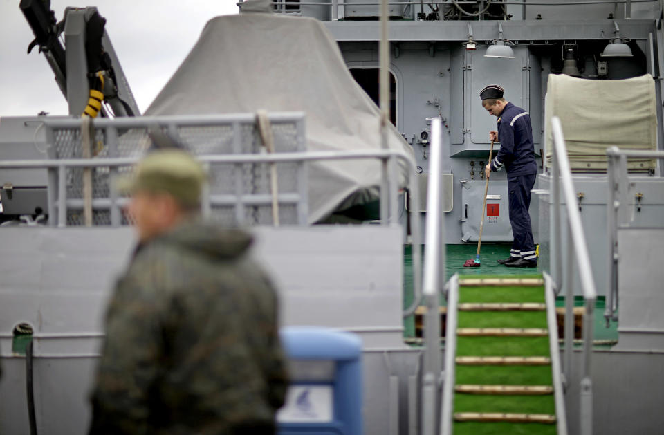 A sailor mops the deck of a Russian military vessel docked in the seaport, Wednesday, Jan. 29, 2014, in Sochi, Russia, home of the upcoming 2014 Winter Olympics. (AP Photo/David Goldman)