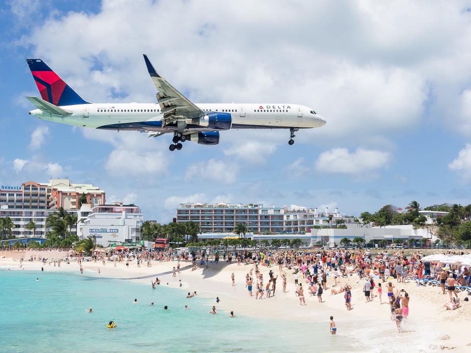 Beachgoers enjoying a Delta airliner fly overhead at Maho Beach.