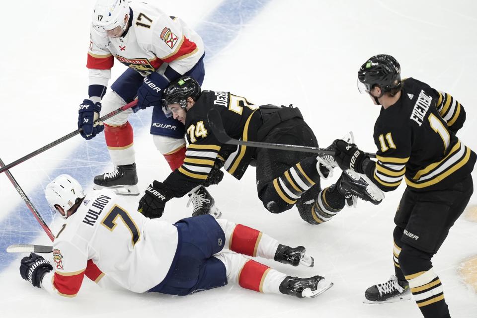 Boston Bruins' Jake DeBrusk (74) and Trent Frederic (11) battle Florida Panthers' Dmitry Kulikov (7) and Evan Rodrigues (17) for the puck during the first period of an NHL hockey game, Saturday, April 6, 2024, in Boston. (AP Photo/Michael Dwyer)
