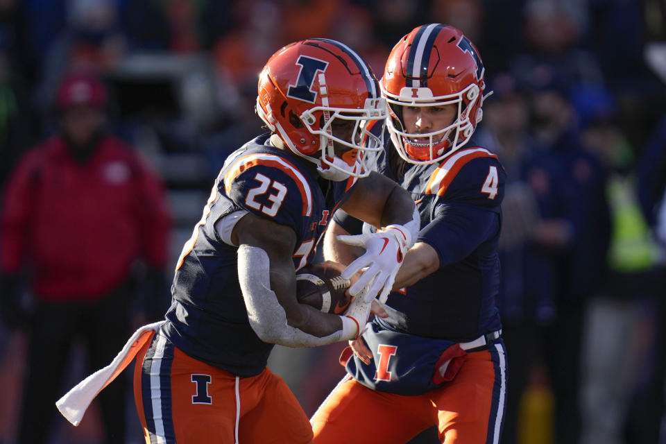 Illinois quarterback John Paddock, right, hands off the ball to running back Reggie Love III, left, during the first half of an NCAA college football game against Northwestern, Saturday, Nov. 25, 2023, in Champaign, Ill. (AP Photo/Erin Hooley)