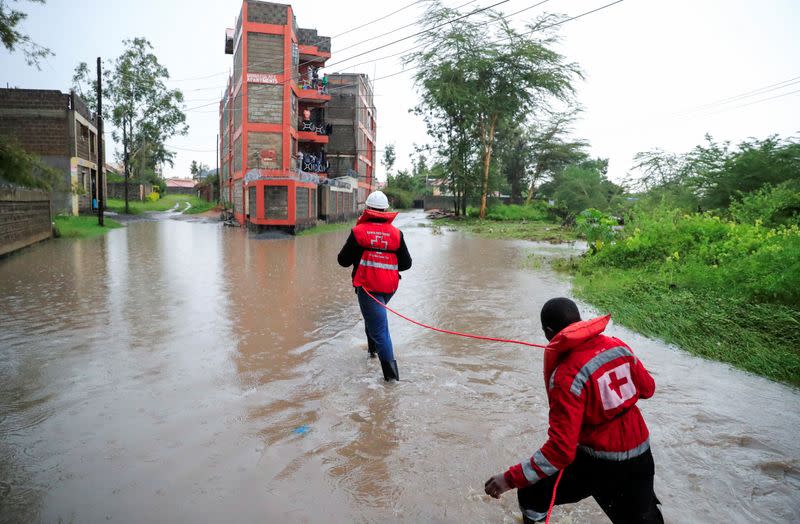 Kenya Red Cross members wade through flood waters to assess and rescue residents trapped in their homes following heavy rainfall in Kitengela municipality of Kajiado County