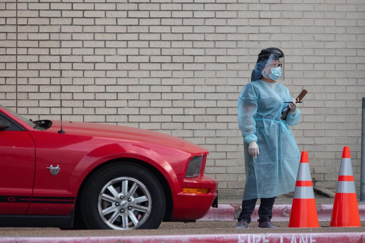 A health care worker assists at a drive-thru COVID-19 testing center at the old Christus Spohn Memorial Hospital parking lot on Sunday, March 29, 2020.