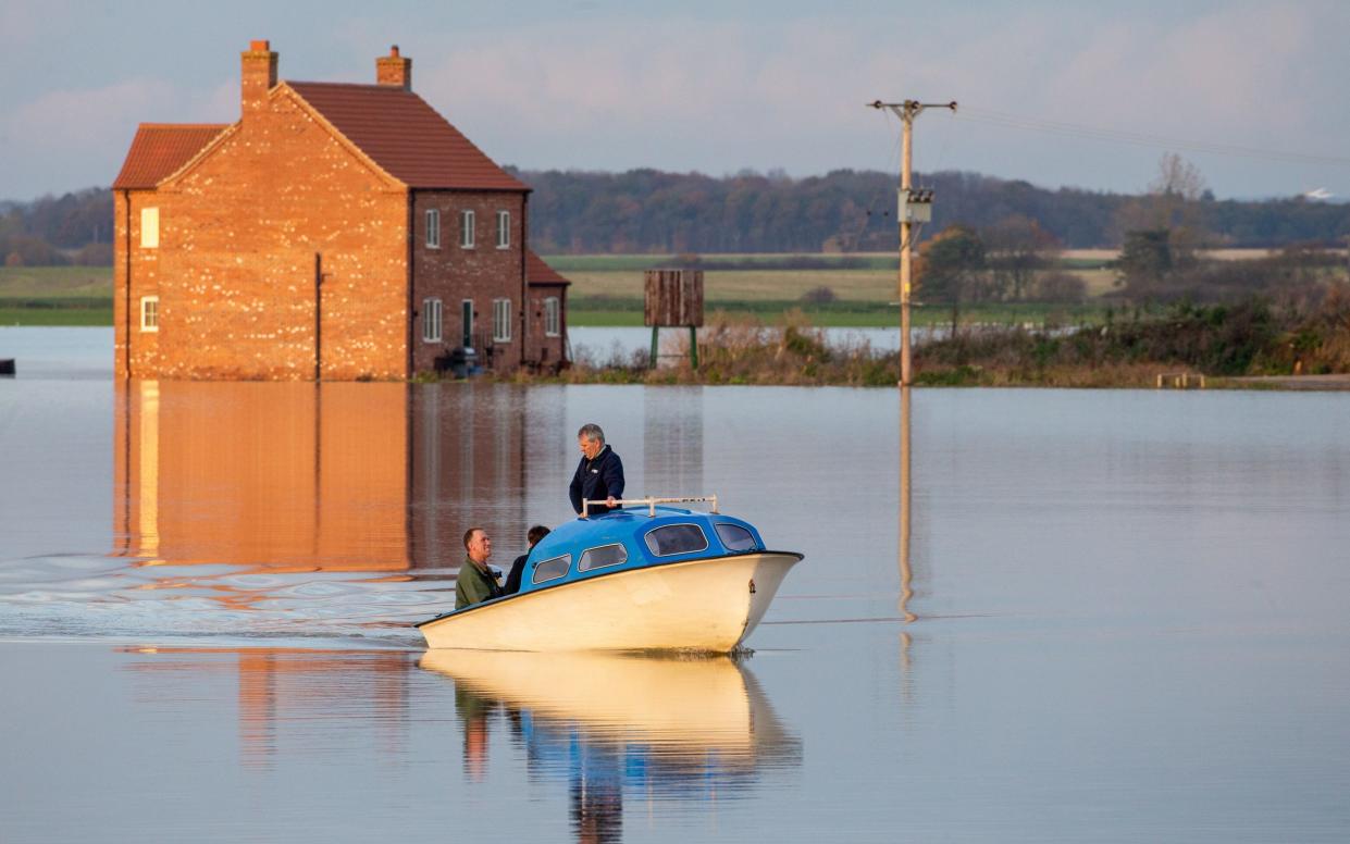 The red brick farmhouse surrounded by still water, with a boat in the foreground