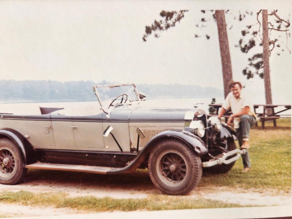 Aubrey Socia, former Reed Ranch manager, with a 1926 Cadillac Lincoln car in front of Shamrock Lake at the Reed Ranch in Oscoda County, Michigan.
