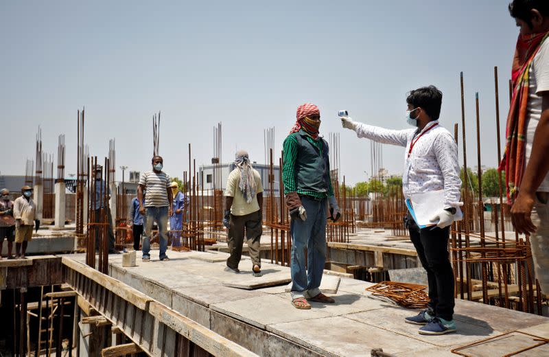 FILE PHOTO: Health worker using an infrared thermometer to measure the temperature of a labourer