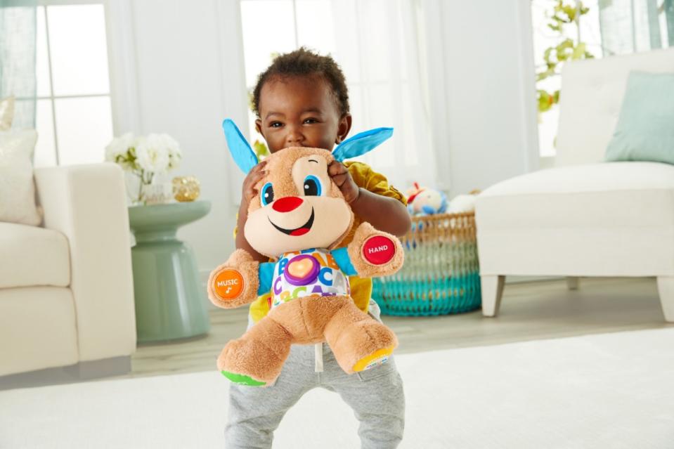 A child playing with the plush, which has buttons on its hands, feet, and chest