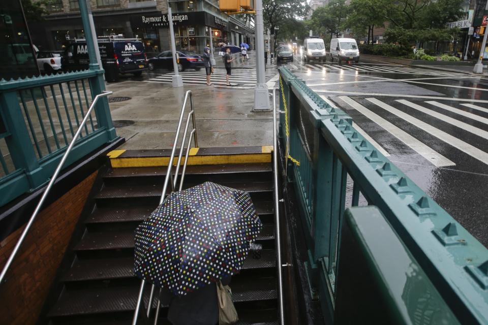A woman uses an umbrella as she exits the Lincoln Center subway station during a rain shower brought about by Tropical Storm Fay, Friday, July 10, 2020, in New York. Beaches closed in Delaware and rain lashed the New Jersey shore as fast-moving Tropical Storm Fay churned north on a path expected to soak the New York City region. (AP Photo/Frank Franklin II)