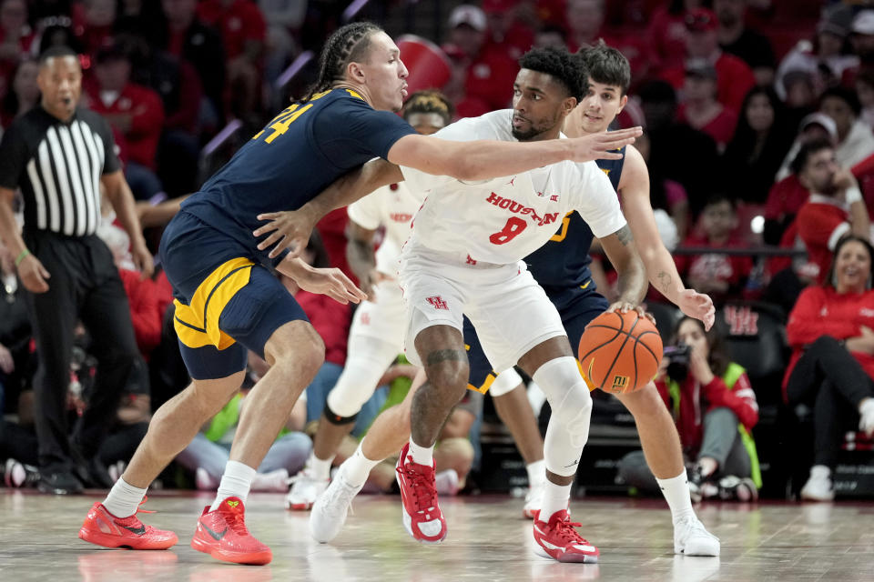 Houston guard Mylik Wilson, right, dribbles as West Virginia forward Patrick Suemnick defends during the second half of an NCAA college basketball game Saturday Jan. 6, 2024, in Houston. (AP Photo/Eric Christian Smith)