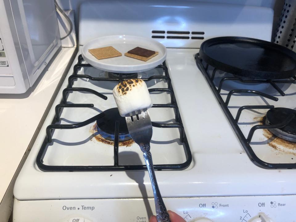 fork with a charred marshmallow on it over a gas stove