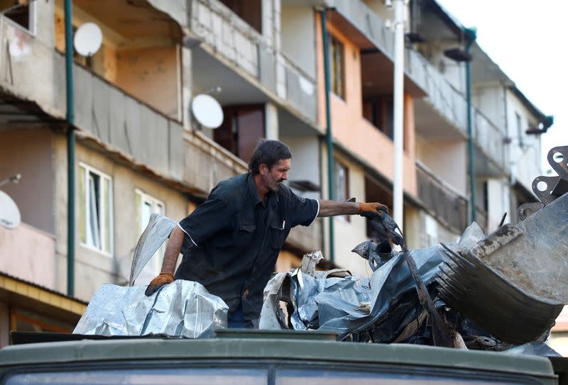 Workers remove debris near a residential building, which was damaged during the military conflict over the breakaway region of Nagorno-Karabakh, in Stepanakert