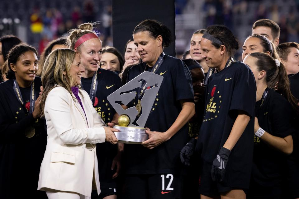 La comisionada de NWSL, Jessica Berman, entrega el trofeo del campeonato a Christine Sinclair de Portland Thorns FC mientras celebran vencer a Kansas City Current en Audi Field.