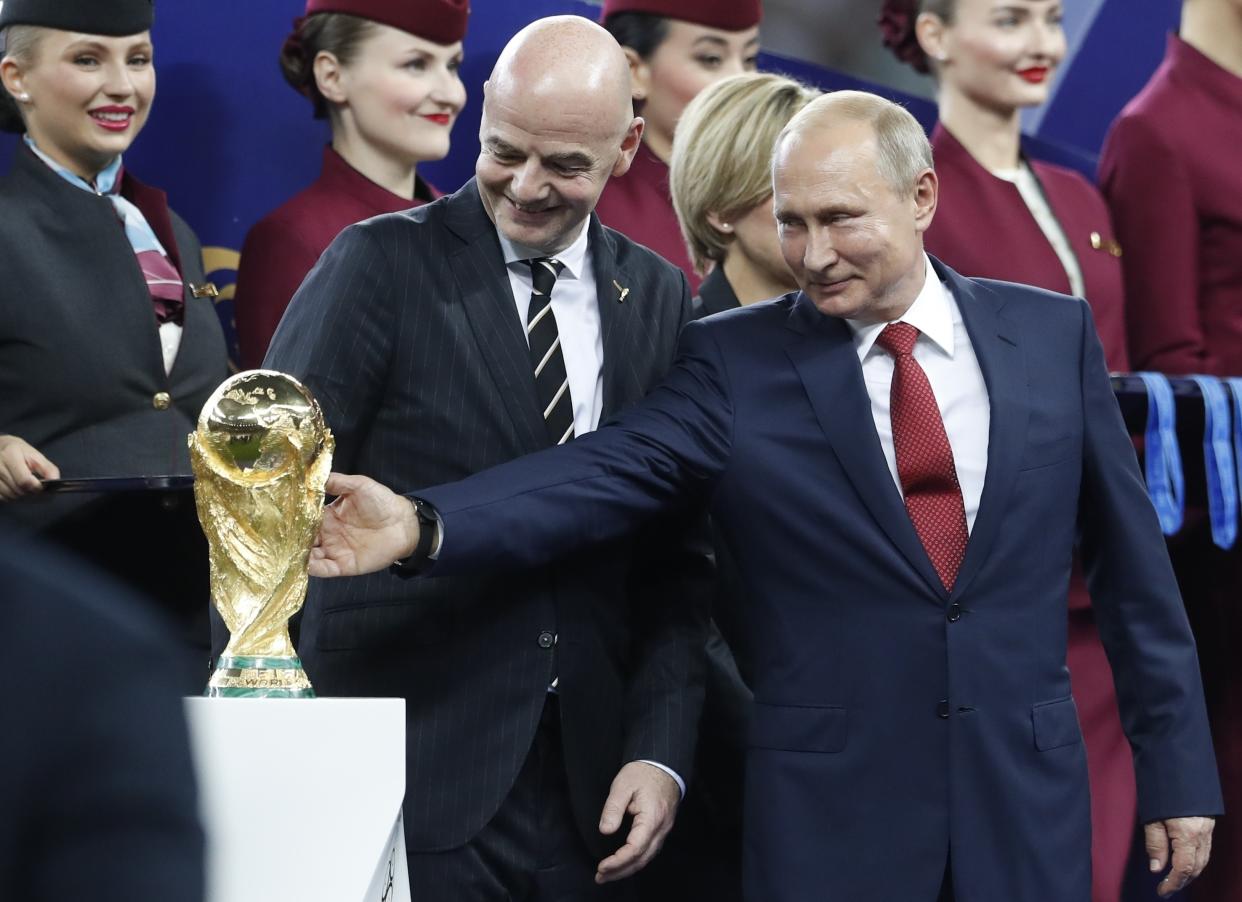 FILE - Russian President Vladimir Putin touches the World Cup trophy as FIFA President Gianni Infantino stands beside him, at the end of the final match between France and Croatia at the 2018 soccer World Cup in the Luzhniki Stadium in Moscow, Russia, Sunday, July 15, 2018. Russia hosted the World Cup party in 2018 but now it's off the guest list. (AP Photo/Petr David Josek, File)