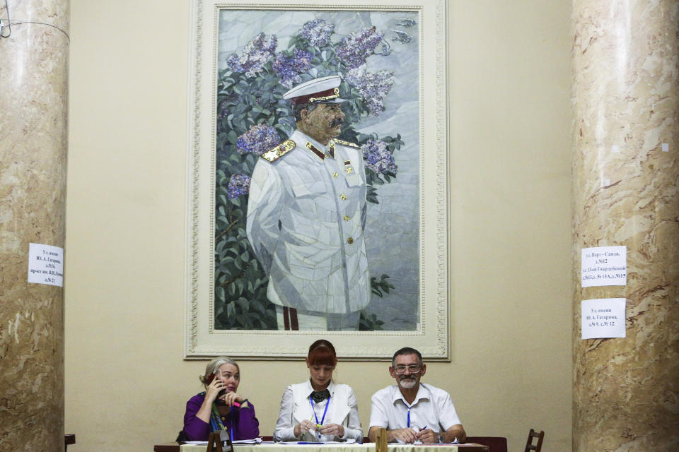 Election commission officials wait for voters at a polling station during governor's and a region's council elections, with the portrait of former Soviet leader Josef Stalin above, in Volgograd, Russia, Sunday, Sept. 8, 2019. Residents of Russia are voting in different local elections that is shadowed by a wave of protests in Moscow that saw the biggest demonstrator turnout in seven years and a notably violent police response. (AP Photo/Dmitriy Rogulin)