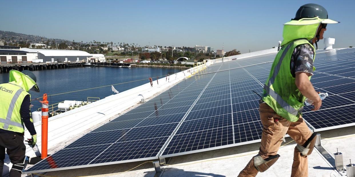 Workers gather as they install solar panels during the completion phase of a 4-acre solar rooftop atop AltaSea's research and development facility at the Port of Los Angeles on April 21, 2023 in the San Pedro neighborhood in Los Angeles, California.