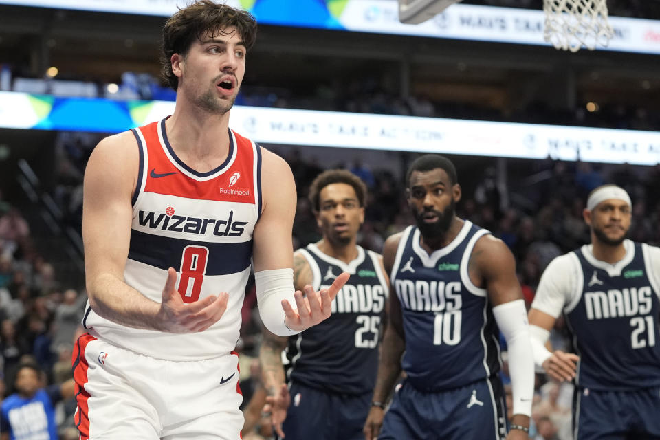 Washington Wizards forward Deni Avdija (8) questions a call as Dallas Mavericks defenders P.J. Washington (25), Tim Hardaway Jr. (10) and Daniel Gafford (21) look on during the second half of an NBA basketball game in Dallas, Monday, Feb. 12, 2024. (AP Photo/LM Otero)