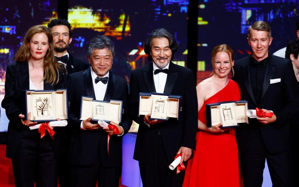 Winners with their awards as they pose for a photo in front of actor Orlando Bloom - Getty