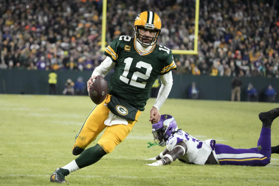 Green Bay Packers quarterback Aaron Rodgers (12) runs from Minnesota Vikings linebacker Brian Asamoah II, right, during a 2-yard touchdown run in the second half of an NFL football game, Sunday, Jan. 1, 2023, in Green Bay, Wis. (AP Photo/Morry Gash)