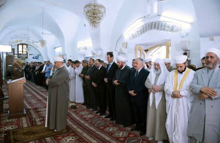 Syria's President Bashar al-Assad (6th L) attends prayers on the first day of the Muslim holiday of Eid al-Fitr, inside a mosque in Hama, in this handout picture provided by SANA on June 25, 2017, Syria. SANA/Handout via REUTERS