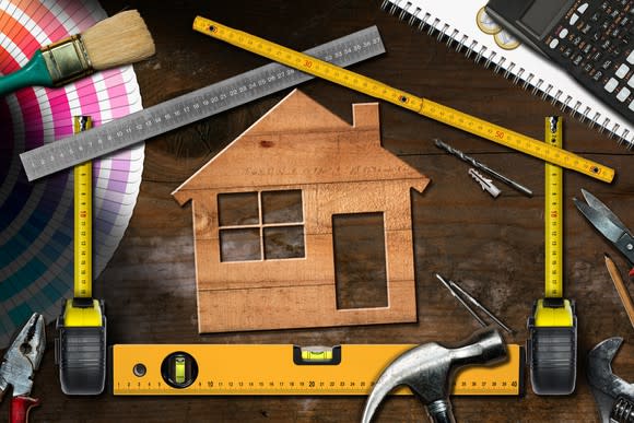 A house stencil amid rulers and home maintenance tools on top of a desk.