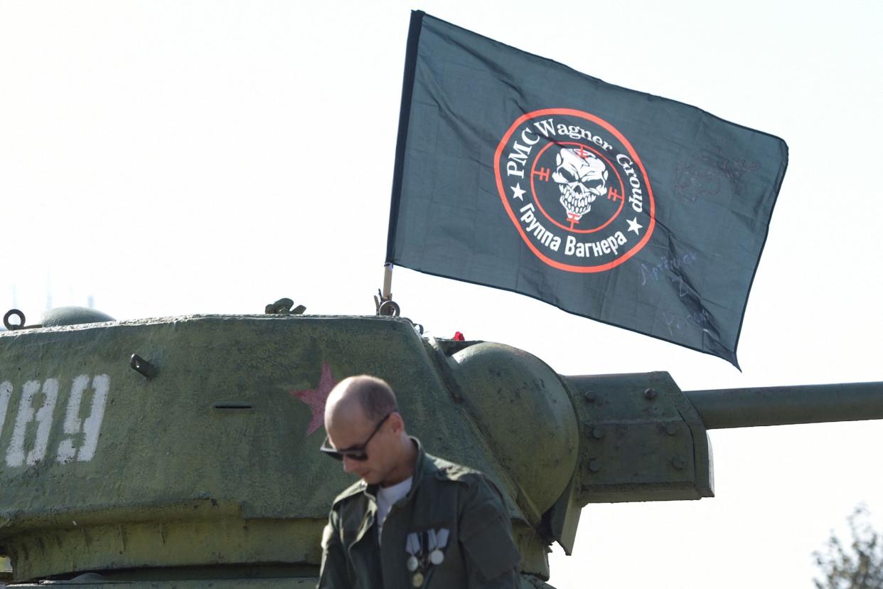 Ein Mann steht vor einer Flagge der Wagner-Gruppe, die auf einem alten Panzer im leninistischen Komsomol-Park in Donezk, der russisch kontrollierten Ukraine, ausgestellt ist, am 1. Oktober 2023. - Copyright: STRINGER/AFP via Getty Images