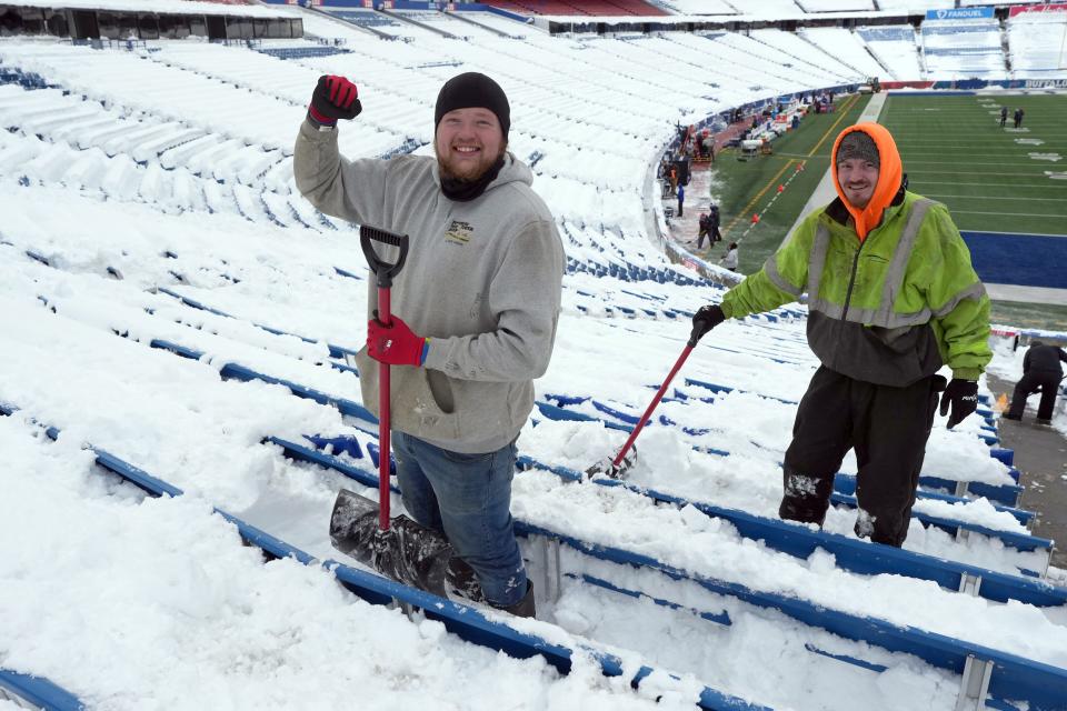 Workers remain in high spirits Monday as they work to clear snow from the stands at Highmark Stadium in Orchard Park, New York.