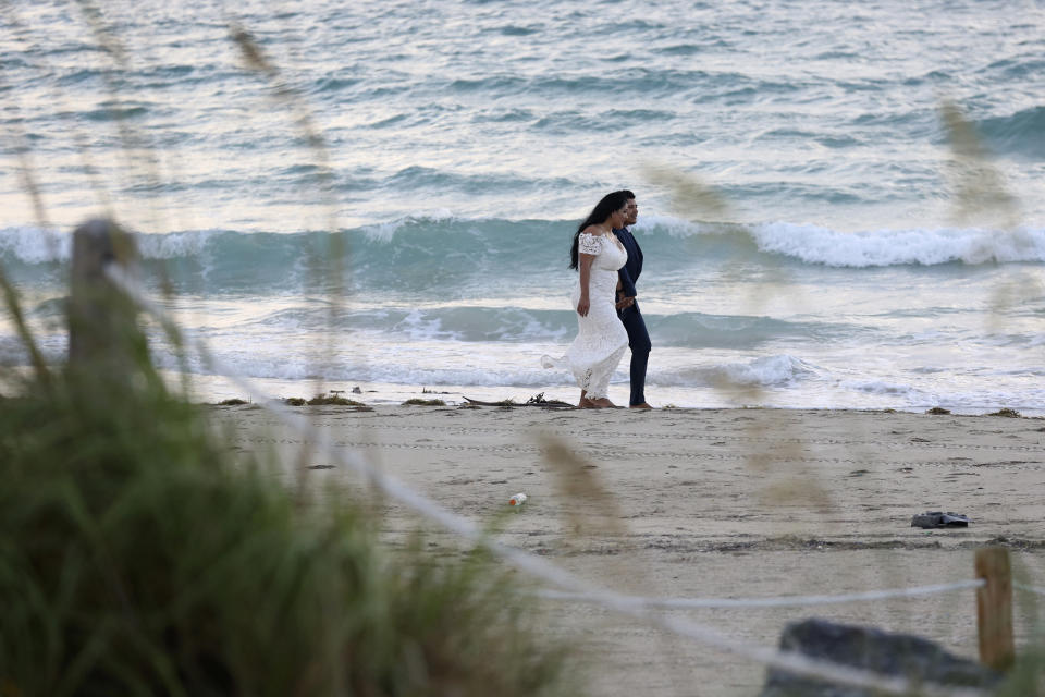 Erica and Valentin Villegas walk along the beach as they are photographed by a wedding photographer, Saturday, Aug. 31, 2019, in Miami Beach, Fla. Forecasters say Hurricane Dorian will threaten the Florida peninsula late Monday or early Tuesday. (AP Photo/Lynne Sladky)