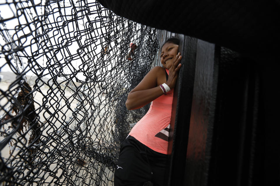 A Honduran migrant, followed by her daughter, squeezes through a gap in the U.S. border wall from Tijuana, Mexico, onto U.S. soil near Imperial Beach, Calif., Sunday, Dec. 9, 2018. Discouraged by the long wait to apply for asylum through official ports of entry, many Central American migrants from recent caravans are choosing to cross the U.S. border wall illegally and hand themselves in to Border Patrol agents to request asylum. (AP Photo/Rebecca Blackwell)