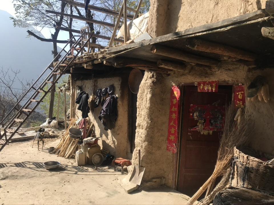 Signs of life including hanging laundry and doorway decorations in ane abandoned village in Lianghekou.