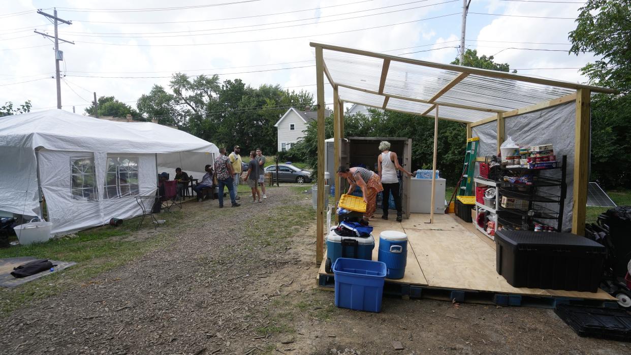 Organizers Elizabeth Blackburn lifts a food container lid as A. Daye looks into a pantry at the homeless camp at 905 E. Mound St. Blackburn and Daye believe the plywood structure caused the city to issue an eviction notice for the residents.