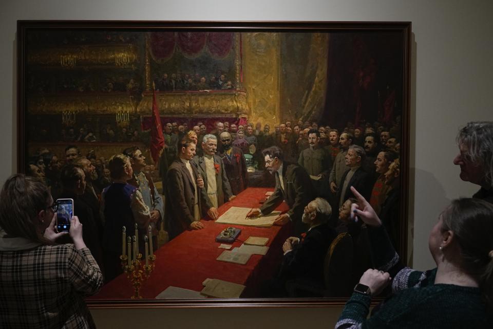 Visitors look at the painting, "The signing of the treaty on the formation of the USSR on December 30, 1922 in the Bolshoi Theater" by Stepan Dudnik at the State Central Museum of Contemporary History of Russia in Moscow, Russia, Wednesday, Dec. 21, 2022. The Soviet Union cast a long shadow after it was founded 100 years ago, but its lifespan was short – dying just a few days short of its 69th birthday. (AP Photo/Alexander Zemlianichenko)