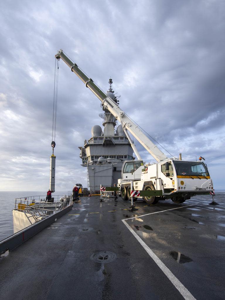 The aircraft French aircraft carrier <em>Charles de Gaulle</em> uses a crane to resupply its stock of Aster Surface-to-Air missiles. <em>French Defense Ministry photo</em>