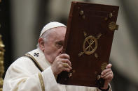 Pope Francis holds the book of Gospels as he celebrates Christmas Eve Mass, at St. Peter's Basilica, at the Vatican, Friday Dec. 24, 2021. Pope Francis is celebrating Christmas Eve Mass before an estimated 1,500 people in St. Peter's Basilica. He's going ahead with the service despite the resurgence in COVID-19 cases that has prompted a new vaccine mandate for Vatican employees. (AP Photo/Alessandra Tarantino)