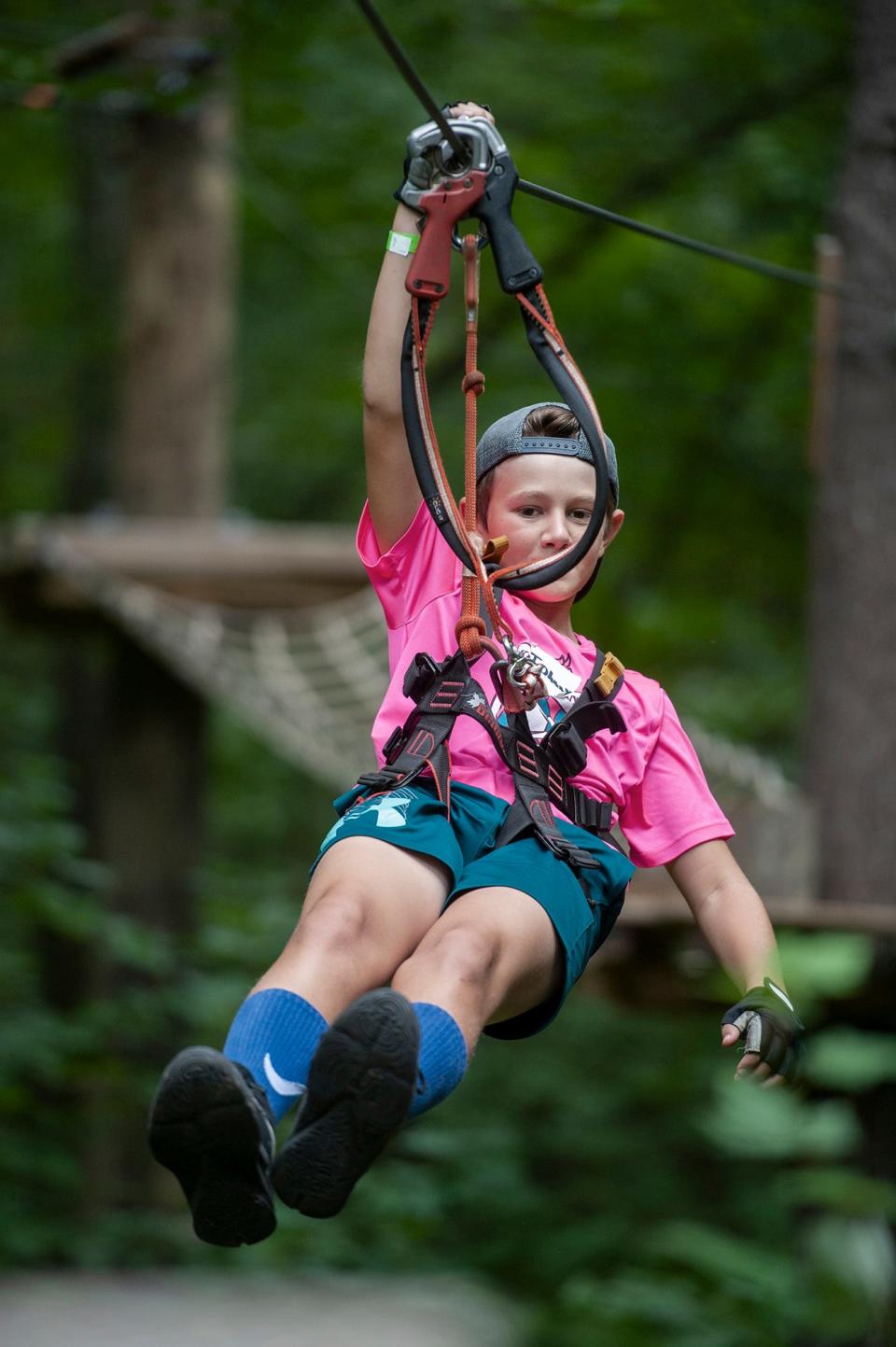 Johnny Phillips, 11, of Concord, travels on a zip line through the forest at Boundless Adventures in West Berlin, Aug. 10, 2022.