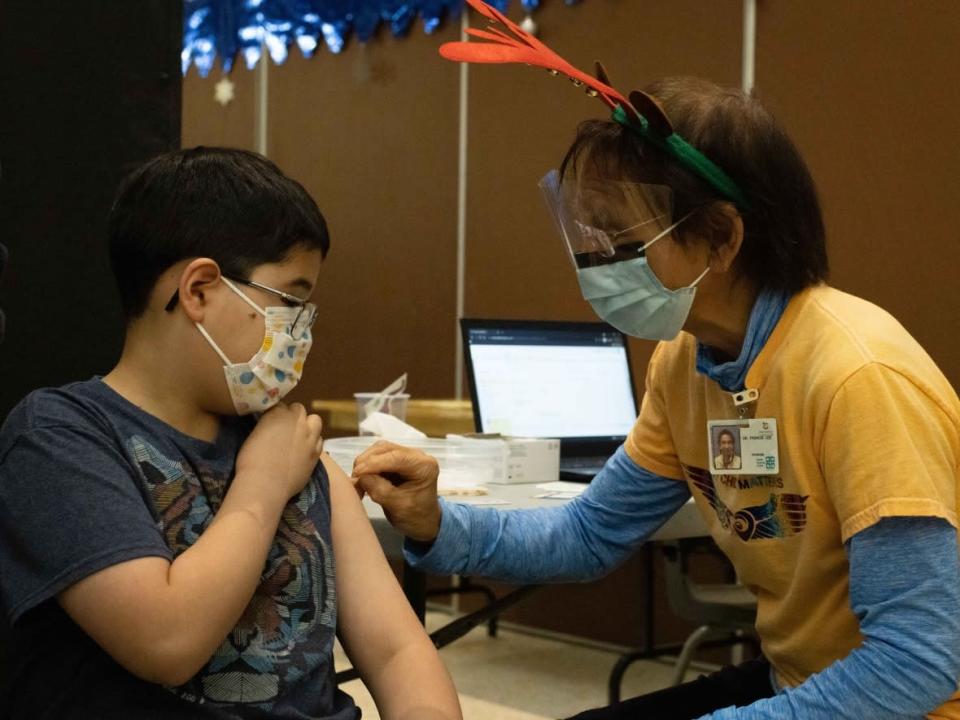Dr. Francis Lee, right, puts a bandaid on Jacob Wolak, 10, after giving him a COVID-19 vaccine in Vancouver, B.C. on Nov. 29, 2021. (Maggie MacPherson/CBC - image credit)