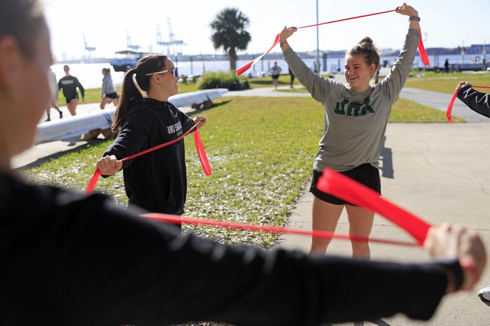 Katy Kost (right) stretches with teammates Isabel Mehrtens before a recent practice session on the St. Johns River for the Jacksonville University women's rowing team.