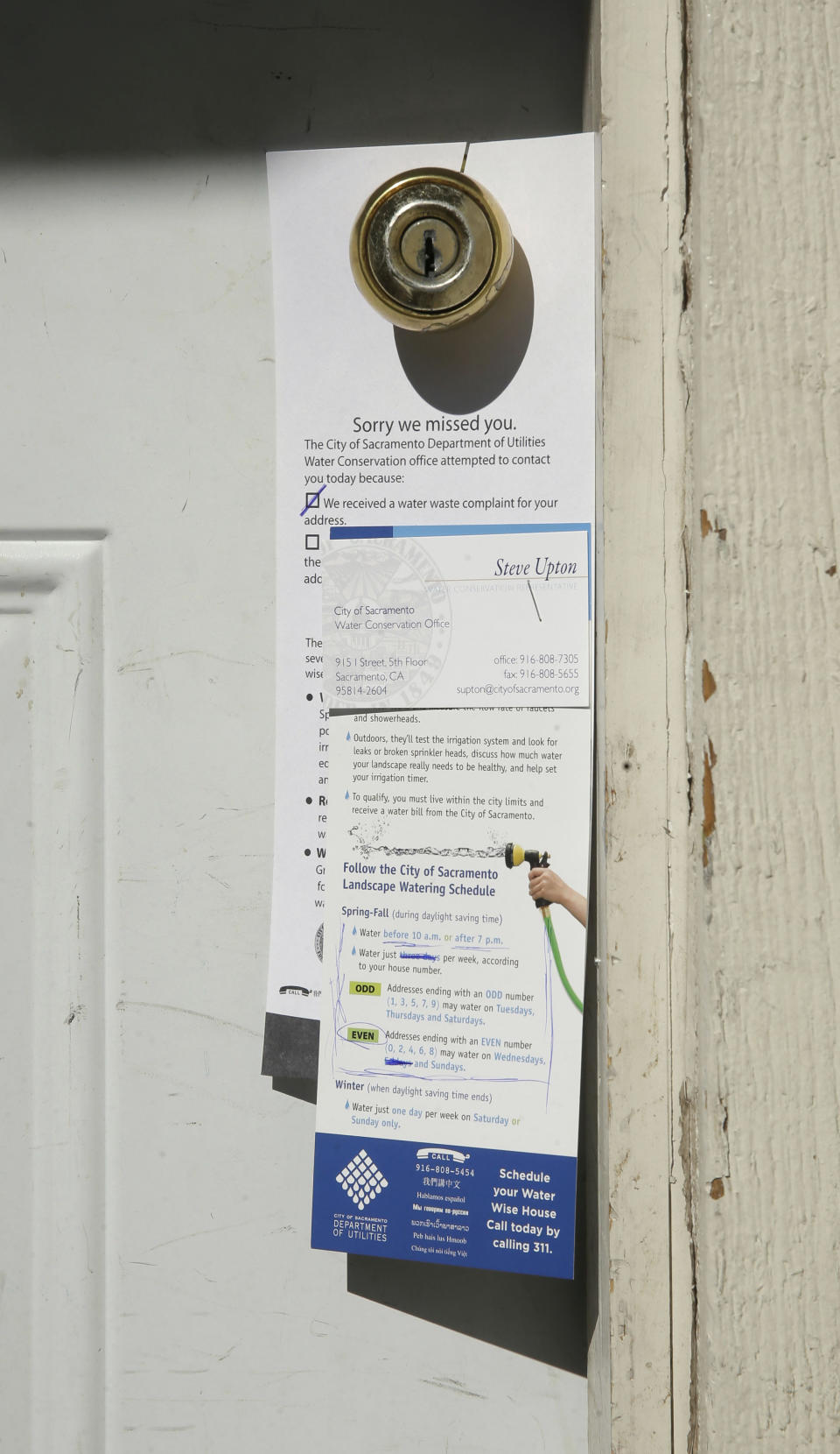 In this photo taken Tuesday, March 11, 2014, an informational door hanger is left by Steve Upton, an inspector for the water conservation unit for the Sacramento Utilities department, on the front door of a residence that a tipster has alleged to have been wasting water in Sacramento, Calif. At least 45 water agencies throughout California have imposed mandatory restrictions on water use as their supplies run dangerously low. In the first three months of the year, Sacramento has received 3,245 water waste complaints with officials issuing 350 violations in a recent two-day sweep to catch people watering their landscaping on the wrong days.(AP Photo/Rich Pedroncelli)