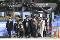 People wearing face masks as a precaution against the coronavirus cross a road in Seoul, South Korea, Friday, Nov. 27, 2020. South Korea's daily virus tally hovered above 500 for the second straight day, as the country's prime minister urged the public to stay home this weekend to contain a viral resurgence. (AP Photo/Ahn Young-joon)