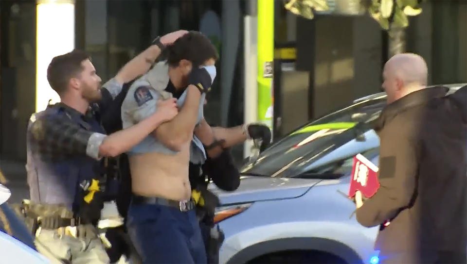 In this image from a video, an injured police officer, second left, is led away to be placed in an ambulance following a shooting in Auckland, New Zealand Thursday, July 20, 2023. A gunman killed and injured people at a construction site in New Zealand’s largest city, as the nation prepared to host games in the FIFA Women’s World Cup soccer tournament, authorities said. (TVNZ via AP)