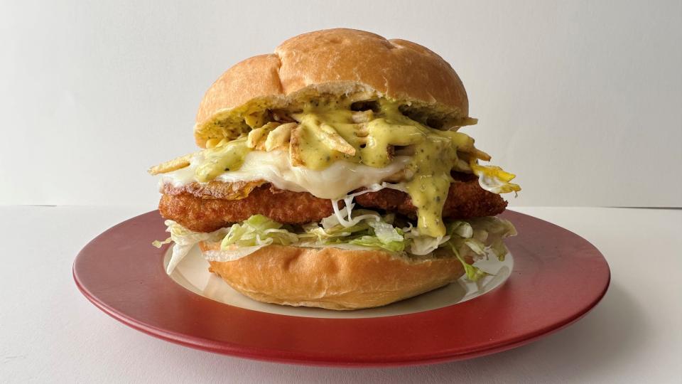 A fried chicken sandwich with a fried egg, shredded lettuce, mozzarella, potato sticks and yellow sauce from the SnowChi Peruvian Cuisine food truck.