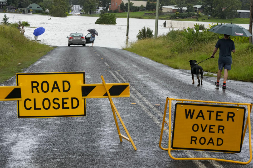 Residents look over a flooded road near Windsor on the outskirts of Sydney, Australia, Thursday, March 3, 2022.Tens of thousands of people had been ordered to evacuate their homes and many more had been told to prepare to flee as parts of Australia's southeast coast are inundated by the worst flooding in decades. (AP Photo/Rick Rycroft)