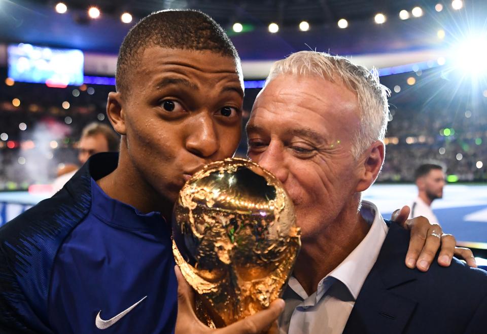 Fance star Kylian Mbappe and head coach Didier Deschamps kiss the World Cup trophy that they won in 2018. (Photo by FRANCK FIFE / AFP)