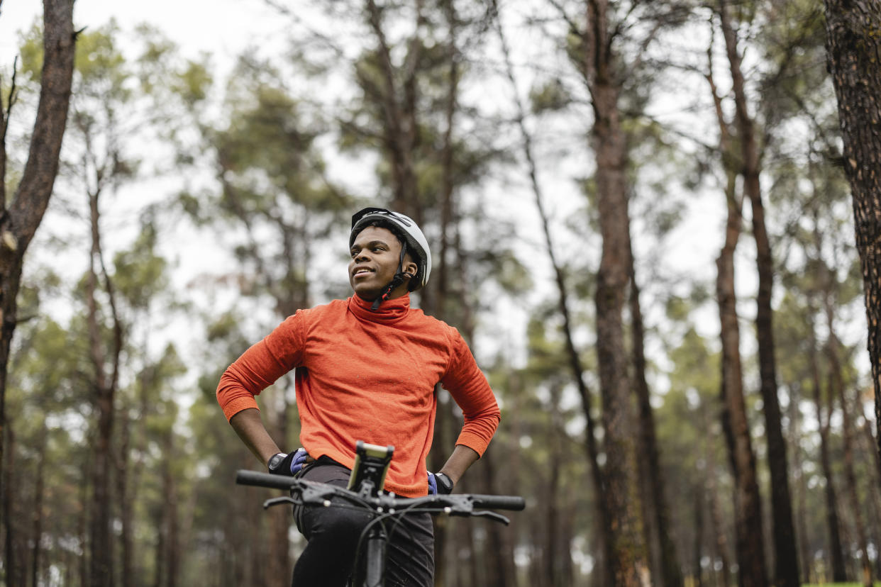 handsome  man with a mountain bike standing in the forest, while looking around.