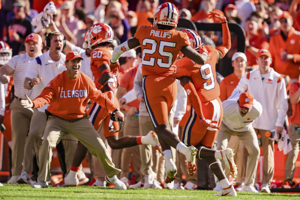 Clemson safety R.J. Mickens (9) celebrates after his interception with safety Jalyn Phillips (25) and head coach Dabo Swinney, left, in the first half of an NCAA college football game against South Carolina on Saturday, Nov. 26, 2022, in Clemson, S.C. (AP Photo/Jacob Kupferman)