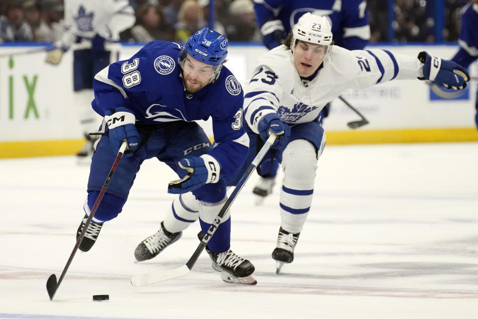 Tampa Bay Lightning left wing Brandon Hagel (38) breaks out ahead of Toronto Maple Leafs left wing Matthew Knies (23) during the second period of an NHL hockey game Tuesday, April 11, 2023, in Tampa, Fla. (AP Photo/Chris O'Meara)