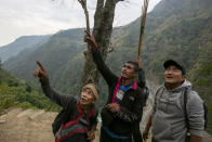 Honey hunters point to a cliff as they prepare to climb a hill carrying tools required for harvesting cliff honey in Dolakha, 115 miles east of Kathmandu, Nepal, Nov. 19, 2021. High up in Nepal's mountains, groups of men risk their lives to harvest much-sought-after wild honey from hives on cliffs. (AP Photo/Niranjan Shrestha)
