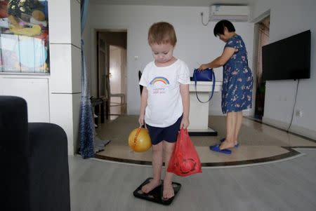 An Zhiya, one of An Hui's and Ye Jianbin's three sons, weighs fruits he carries, next to his grandmother at home in Shenzhen, Guangdong province, China September 17, 2018. An and Ye are fathers of triplets who were conceived with the help of a German egg donor. REUTERS/Jason Lee